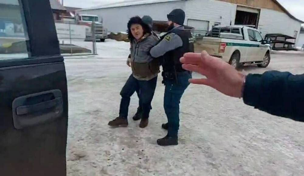 Stills from a video posted on Wesley Bone’s Twitter account show Parks Canada officers arresting him at a gas station in Strathclair, Man. Bone had lived at Lake Audy in Riding Mountain National Park since December 2019. (Screenshot)
