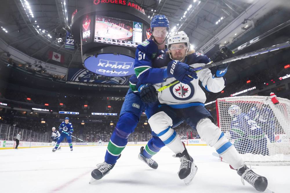 DARRYL DYCK / THE CANADIAN PRESS
Vancouver Canucks’ Tyler Myers, back, checks Winnipeg Jets’ Adam Lowry during the first period.
