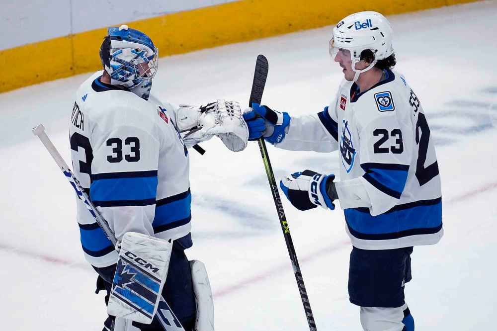 David Rittich (left) celebrates with centre Michael Eyssimont after the Jets defeated the Chicago Blackhawks 3-1. (Nam Y. Huh / The Associated Press)