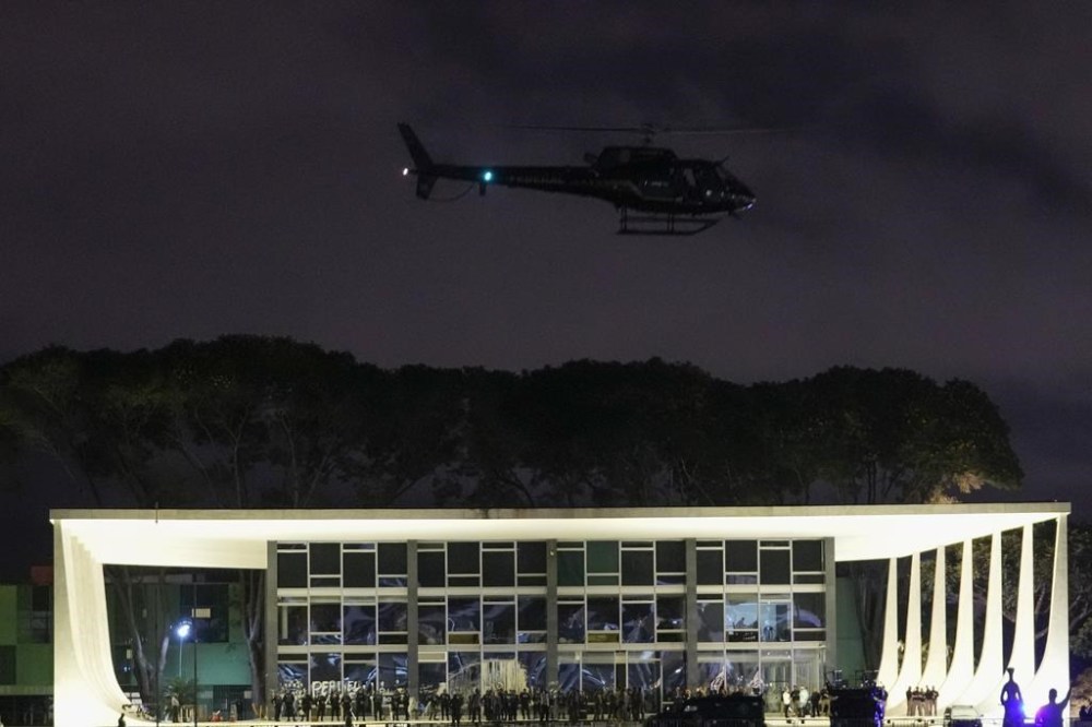 A Police helicopter flies over the Planalto Palace after it was stormed and vandalized by supporters of Brazil's former President Jair Bolsonaro in Brasilia, Brazil, Sunday, Jan. 8, 2023. Protesters who refuse to accept Bolsonaro´s election defeat stormed Congress, the Supreme Court and presidential palace in the capital, a week after the inauguration of his rival, President Luiz Inacio Lula da Silva. (AP Photo/Eraldo Peres)