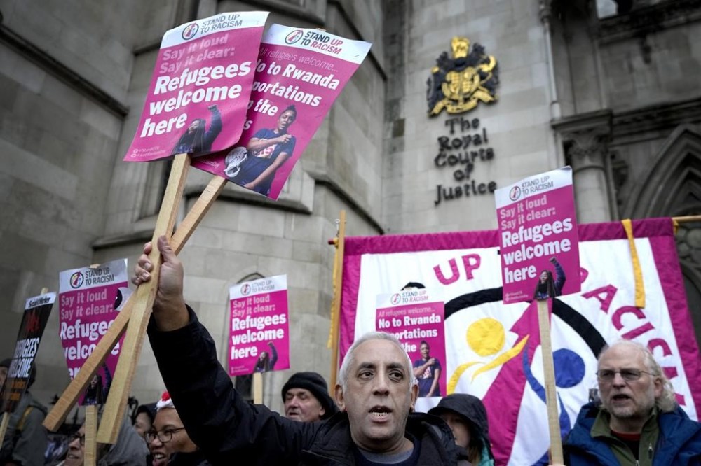 FILE - Stand Up To Racism campaigners hold banners outside the High Court in London, Monday, Dec. 19, 2022. British judges gave the go-ahead Monday, Jan. 16, 2023 for the Court of Appeal to consider challenges to the British government’s plan to send some asylum-seekers on a one-way trip to Rwanda. Two High Court judges ruled in December that the controversial policy is legal, rejecting a lawsuit from several asylum-seekers, aid groups and a border officials’ union. (AP Photo/Kirsty Wigglesworth, File)