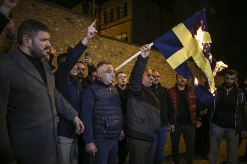 People set on fire a Sweden flag during a small protest outside the Swedish consulate in Istanbul, Turkey, Saturday, Jan. 21, 2023. Turkey on Saturday canceled a planned visit by Sweden's defense minister in response to anti-Turkish protests that increased tension between the two countries as Sweden seeks Turkey's approval to join NATO. (AP Photo/Emrah Gurel)