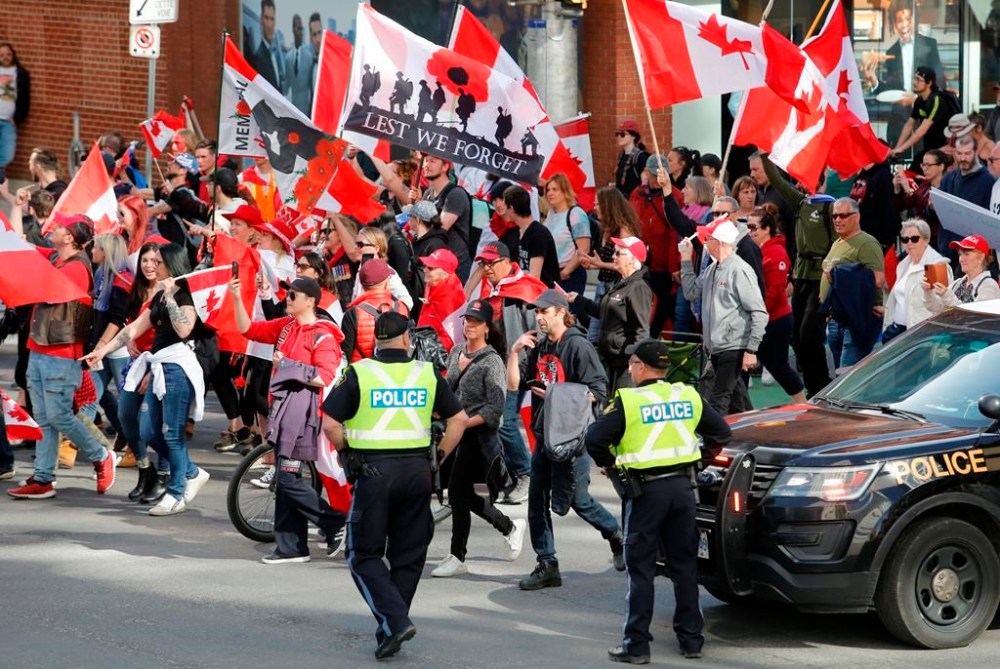 People march past police at a demonstration, part of a convoy-style protest, in Ottawa, on Saturday, April 30, 2022. The Ottawa People's Commission says last winter's weeks-long