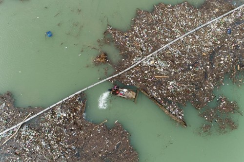 Utility company workers push the waste to the shore of Lim river near Priboj, Serbia, Monday, Jan. 30, 2023. Plastic bottles, wooden planks, rusty barrels and other garbage dumped in poorly regulated riverside landfills or directly into the rivers accumulated during high water season, behind a trash barrier in the Lim river in southwestern Serbia. (AP Photo/Armin Durgut)