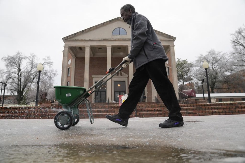 Terry Lawrence, of Memphis, Tenn., spreads ice melting salt around Mississippi Boulevard Christian Church where a funeral service for Tyre Nichols will be held after a delay due to weather on Wednesday, Feb. 1, 2023, in Memphis, Tenn. Nichols was beaten by Memphis police officers, and later died from his injuries. (AP Photo/Jeff Roberson)