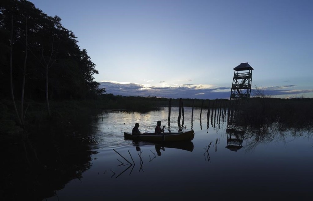Two people row on a lake in the Valentin Gomez Farias communal farmlands near the Calakmul Biosphere Reserve in the Yucatan Peninsula of Mexico on Wednesday, Jan. 11, 2023. Residents created an ecotourism project nine years ago that has visitors staying in tents under roofs of woven palm. (AP Photo/Marco Ugarte)