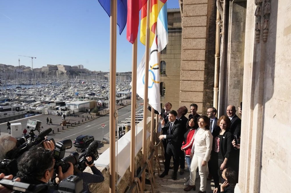 Mayor of Marseille Benoit Payan, left, raises the Olympic flag with Head of Paris 2024 Olympics Tony Estanguet, center, after a press conference at Marseille City Hall, southern France, Friday, Feb. 3. 2023. Instead of arriving overland, the symbolic flame alighting the Paris 2024 Games will take to the seas from its birthplace in Greece, arriving aboard a three-masted tall ship in the French port of Marseille. (AP Photo/Thibault Camus)