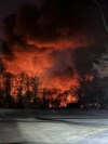 In this photo provided by Melissa Smith, a train fire is seen from her farm in East Palestine, Ohio, Friday, Feb. 3, 2023. A train derailment and resulting large fire prompted an evacuation order in the Ohio village near the Pennsylvania state line on Friday night, covering the area in billows of smoke lit orange by the flames below. (Melissa Smith via AP)