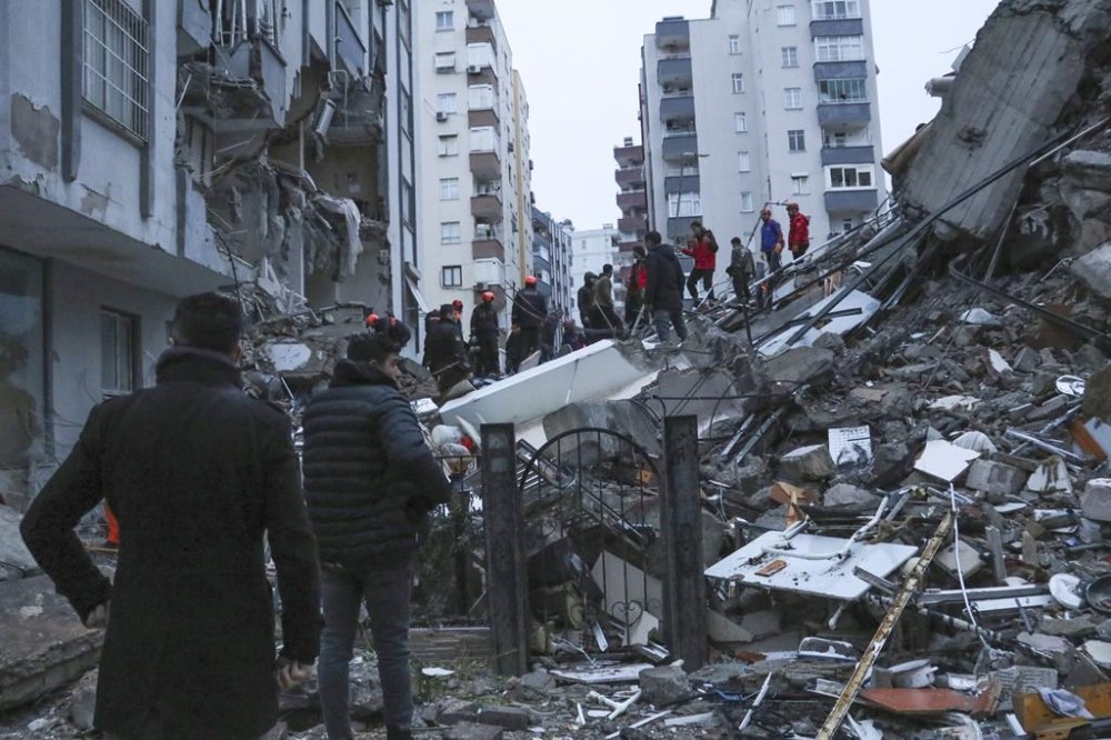 People and rescue teams try to reach trapped residents inside collapsed buildings in Adana, Turkey, Monday, Feb. 6, 2023. A powerful quake has knocked down multiple buildings in southeast Turkey and Syria and many casualties are feared. (IHA agency via AP)