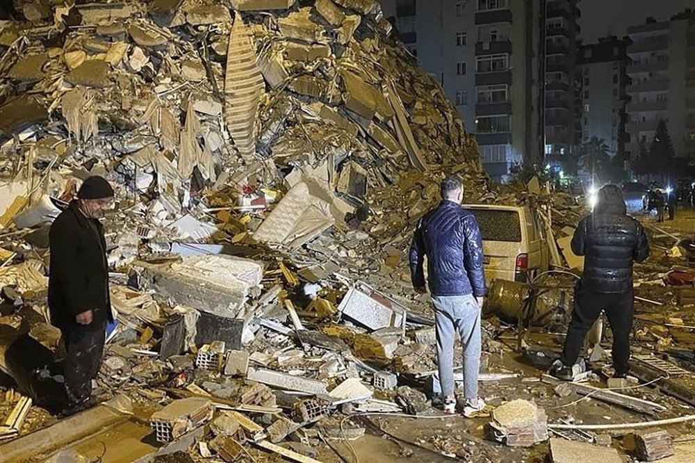 People try to reach trapped residents inside collapsed buildings in Diyarbakir, southern Turkey, early Monday, Feb. 6, 2023. A powerful earthquake has caused significant damage in southeast Turkey and Syria and many casualties are feared. Damage was reported across several Turkish provinces, and rescue teams were being sent from around the country. (Depo Photos via AP)