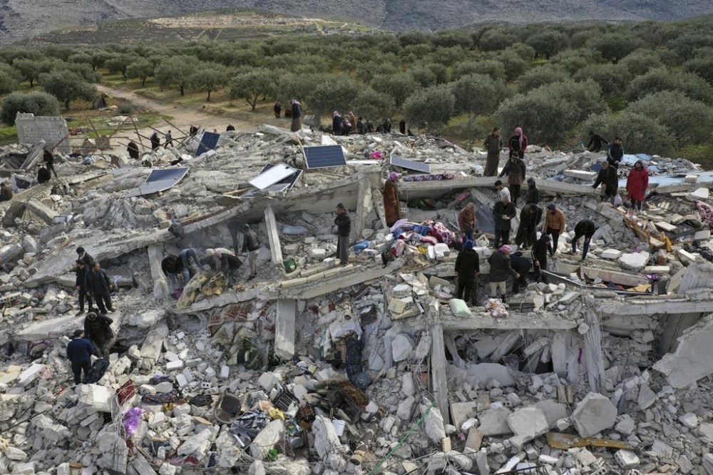 Civil defense workers and residents search through the rubble of collapsed buildings in the town of Harem near the Turkish border, Idlib province, Syria, Monday, Feb. 6, 2023. A powerful earthquake has caused significant damage in southeast Turkey and Syria and many casualties are feared. Damage was reported across several Turkish provinces, and rescue teams were being sent from around the country. (AP Photo/Ghaith Alsayed)