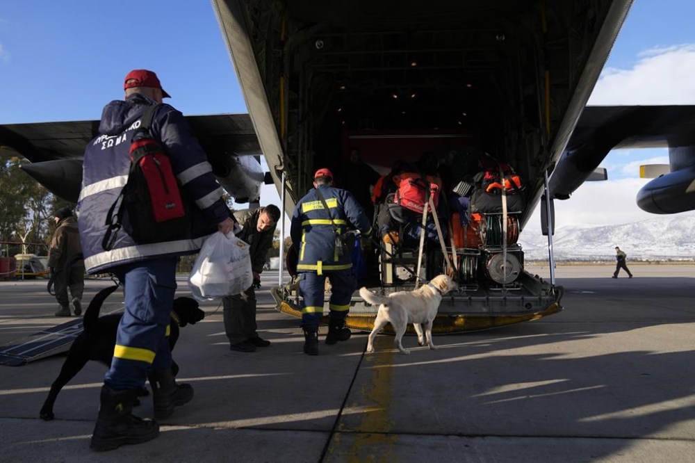 Greek firefighters with dogs board a military plane at Elefsina Air Force Base, in western Athens, Greece, Monday, Feb. 6, 2023. Greece announced it is sending a team of 21 rescuers, two rescue dogs and a special rescue vehicle, together with a structural engineer, five doctors and seismic planning experts, all traveling in a military transport plane. (AP Photo/Thanassis Stavrakis)