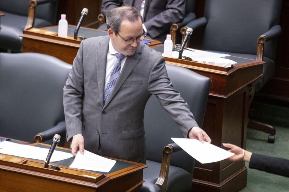 Ontario Attorney General Doug Downey hands over paperwork to a page in the Queens Park Legislature, in Toronto, on Thursday June 10, 2021. Indigenous leaders and the province have opened a centre in northwest Ontario in an effort to address the overrepresentation of Indigenous people in the justice system.THE CANADIAN PRESS/Chris Young