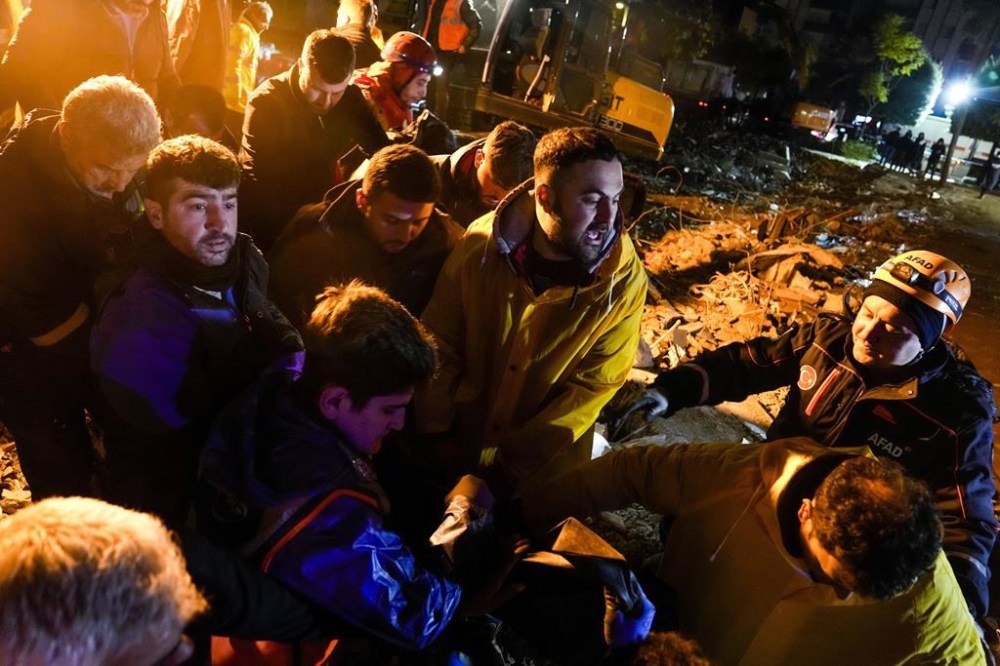 Emergency team members carry the body of a person found in the rubble of a destroyed building in Adana, Turkey, Monday, Feb. 6, 2023. A powerful earthquake that struck southeast Turkey and northern Syria has killed more than 640 people with hundreds injured. The toll is expected to rise as rescuers search for dead and survivors in dozens of collapsed buildings across the region. (AP Photo/Khalil Hamra)