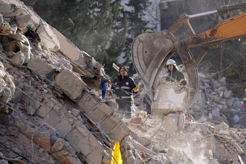 Emergency teams search for people in the rubble of a destroyed building in Adana, southern Turkey, Tuesday, Feb. 7, 2023. A powerful earthquake hit southeast Turkey and Syria early Monday, toppling hundreds of buildings and killing and injuring thousands of people. (AP Photo/Hussein Malla)