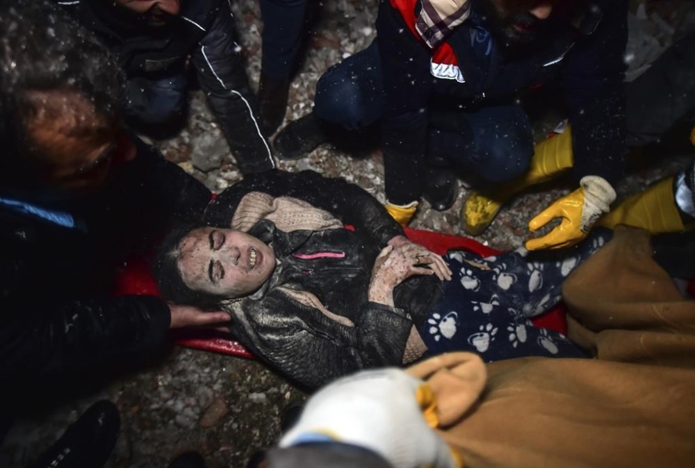 Rescue workers and medics carry a woman out of the debris of a collapsed building in Elbistan, Kahramanmaras, in southern Turkey, Tuesday, Feb. 7, 2023. Rescuers raced Tuesday to find survivors in the rubble of thousands of buildings brought down by a 7.8 magnitude earthquake and multiple aftershocks that struck eastern Turkey and neighboring Syria. (Ismail Coskun/IHA via AP)