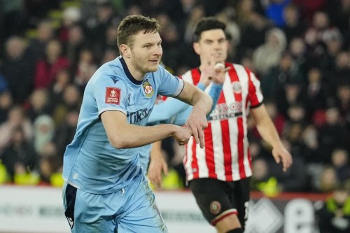 Wrexham's Paul Mullin, left, celebrates after scoring his side's opening goal from a penalty shot during the FA Cup 4th round soccer match between Sheffield United and Wrexham at the Bramall Lane stadium in Sheffield, England, Tuesday, Feb. 7, 2023. (AP Photo/Jon Super)