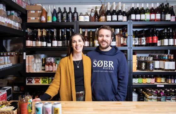 Jessie and Shane Halliburton of The Søbr Market pose in front of some of the low/no-alcohol wines and other products they carry in their online store. (Jessica Lee / Winnipeg Free Press)