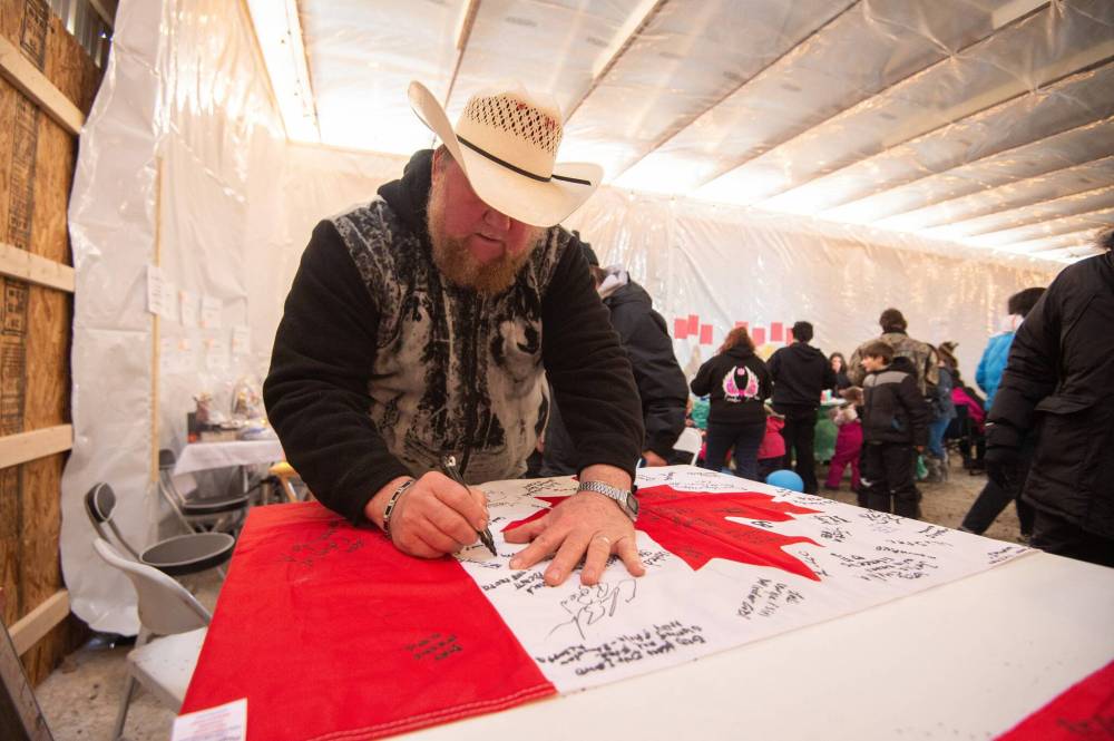 MIKE SUDOMA / WINNIPEG FREE PRESS
Camp Hope owner Walter Hiebert signs his name and writes a message on a Canadian flag.