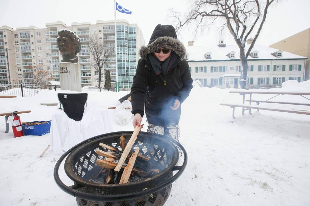 JOHN WOODS / WINNIPEG FREE PRESS
                                Kyra De La Ronde puts wood on the fire at the Louis Riel Day celebration at the Saint Boniface Museum.