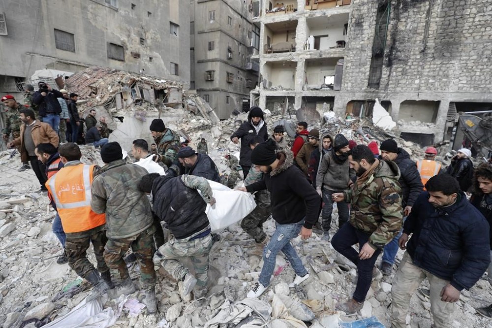 Rescue teams carry the body of a victim from a destroyed building in Aleppo, Syria, Tuesday, Feb. 7, 2023. Rescuers raced Tuesday to find survivors in the rubble of thousands of buildings brought down by a powerful earthquake and multiple aftershocks that struck eastern Turkey and neighboring Syria. (AP Photo/Omar Sanadiki)