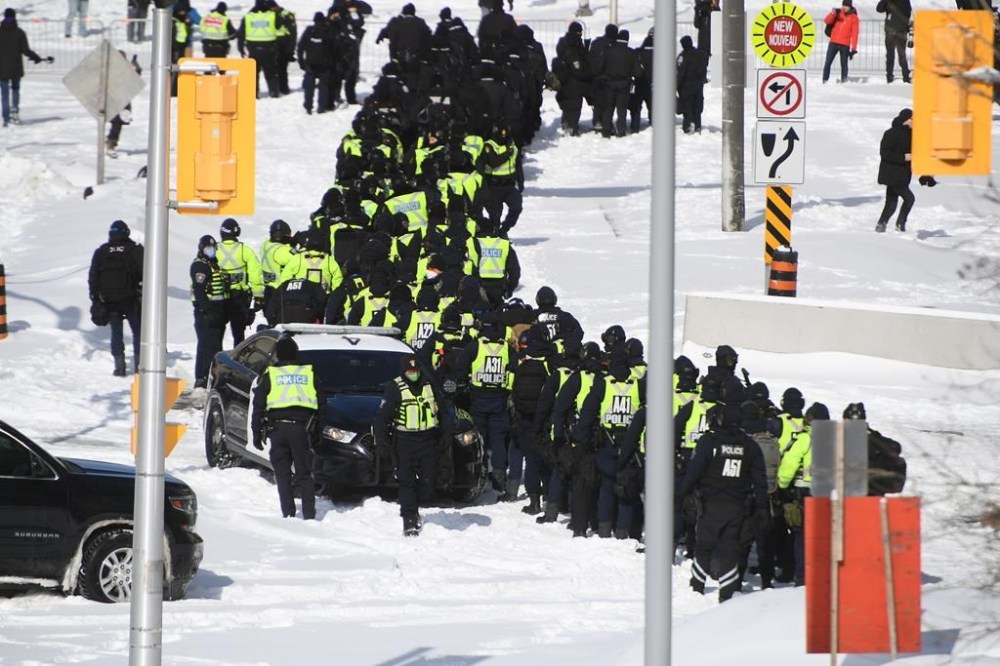 A lineup of police officers assemble on Colonel By Drive near the truck blockade in Ottawa, on Friday, Feb. 18, 2022. Ottawa’s Auditor General says the city’s council, police service and civilian oversight board can communicate more efficiently when responding to major, emergency events in a report examining how the Freedom Convoy was handled. THE CANADIAN PRESS/Justin Tang