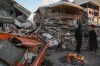 People stand by collapsed buildings in Golbasi, in Adiyaman province, southern Turkey, Wednesday, Feb. 8, 2023. A team of urban search and rescue specialists from British Columbia has deployed to Turkey's earthquake zone after independently offering to help with what one Turkish official described as a race against time to find survivors in frigid conditions. THE CANADIAN PRESS/AP, Emrah Gurel