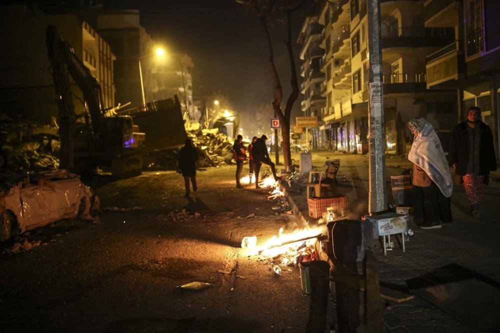 A woman tries to warm next to a fire, in Adiyaman, southeastern Turkey, Wednesday, Feb. 8, 2023. With hope of finding survivors fading, stretched rescue teams in Turkey and Syria searched Wednesday for signs of life in the rubble of thousands of buildings toppled by the world's deadliest earthquake in more than a decade. (AP Photo/Emrah Gurel)