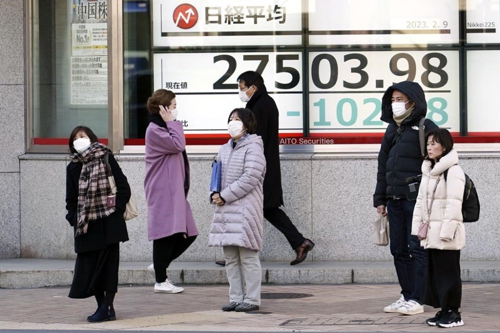 People stand in front of an electronic stock board showing Japan's Nikkei 225 index at a securities firm Thursday, Feb. 9, 2023, in Tokyo. Shares fell Thursday in Asia after Wall Street gave back some of its recent gains on persisting uncertainty over interest rates and inflation. (AP Photo/Eugene Hoshiko)