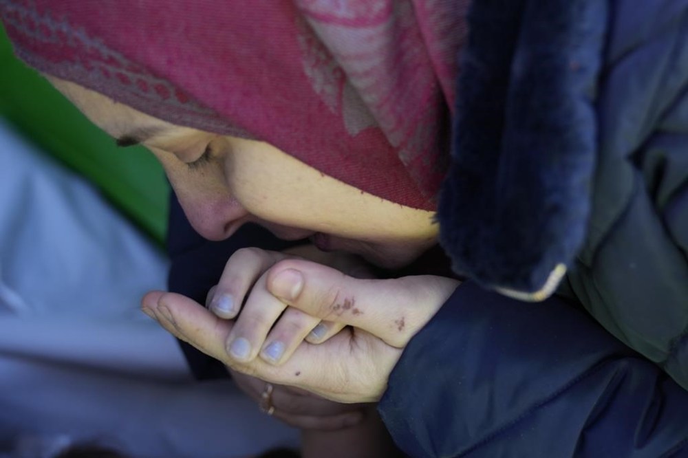 A mother from Syria kisses the hand of her dead daughter, who was earthquake victim and will be transported to Syria for burial, from the Turkish crossing point of Cilvegozu, in Reyhanli, southeastern Turkey, Thursday, Feb. 9, 2023. Rescuers pulled more survivors from beneath the rubble of collapsed buildings Thursday, but hopes were starting to fade of finding many more people alive more than three days after a catastrophic earthquake and series of aftershocks hit Turkey and Syria. (AP Photo/Hussein Malla)
