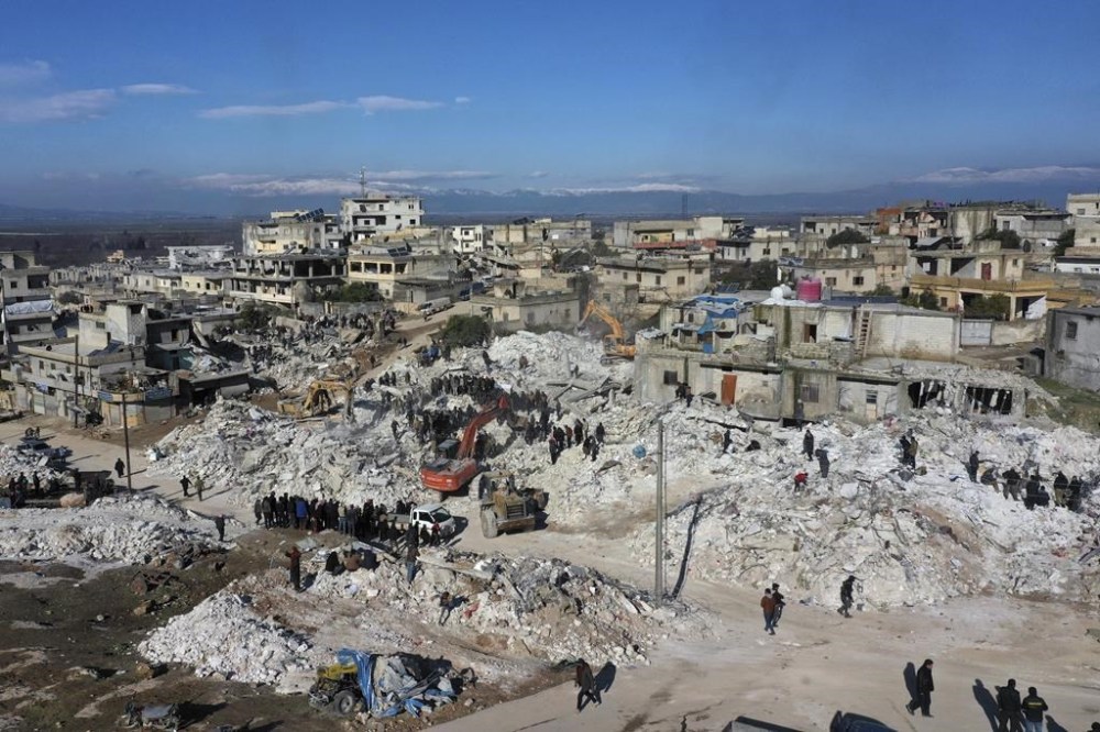 Rescuers and residents search through the rubble of collapsed buildings in the town of Harem near the Turkish border, Idlib province, Syria, Wednesday, Feb. 8, 2023. This week's earthquake that devastated parts of southern Turkey and northern Syria left unknown numbers of orphans. In many cases, extended family members are taking in orphans, but often they too are struggling after their own homes have been destroyed. (AP Photo/Ghaith Alsayed)