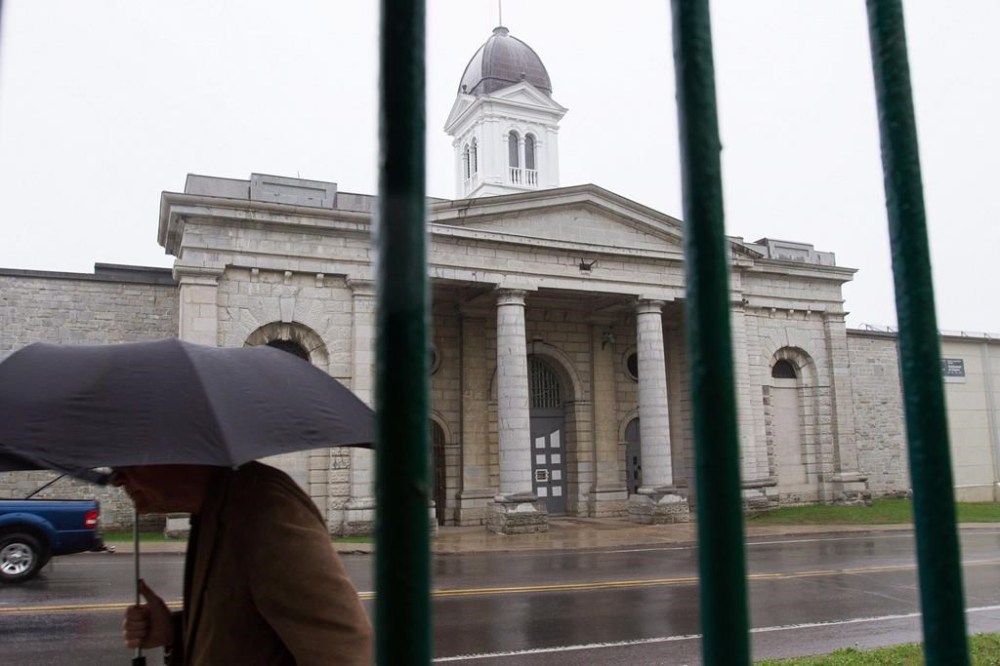 A pedestrian walks by the former Kingston penitentiary in Kingston Ont., on Friday May 13, 2016. Canada's top corrections officials are being pressed by parliamentarians to improve conditions for Black and Indigenous offenders serving time in federal prisons. THE CANADIAN PRESS/Lars Hagberg