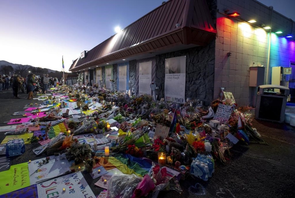 FILE - Mourners gather outside Club Q to visit a memorial, which has been moved from a sidewalk outside of police tape that was surrounding the club, Nov. 25, 2022, in Colorado Spring, Colo. A defense attorney says the person charged with fatally shooting five people and wounding multiple others at the gay nightclub in was at the venue for more than an hour earlier that night before carrying out the mass shooting. (Parker Seibold/The Gazette via AP, File)