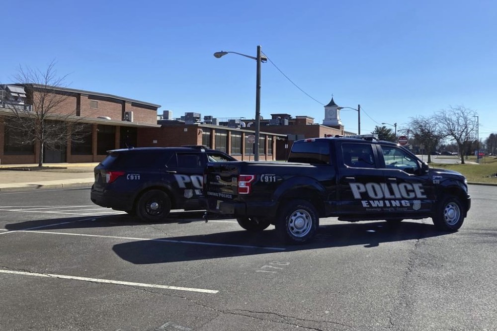 Two Ewing, NJ, Police vehicles are parked on the campus of Ewing High School, Tuesday, Feb. 14, 2023. The school district was closed after a warning stemming from the Michigan State University shooting. An unidentified officer at the scene said they were stationed there because of the warning. (AP Photo/Mike Catalini)