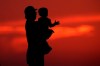 A British Columbia advocacy organization says child poverty decreased in the province in 2020 due to government benefits launched in response to the COVID-19 pandemic, but the progress may be wiped out by rising living costs. A silhouette against the sky of a man holding a child in Kansas City, Mo., Friday, June 26, 2020. THE CANADIAN PRESS/AP-Charlie Riedel