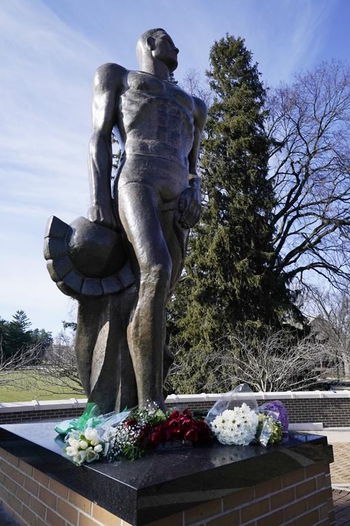 Flowers are placed at the Spartan Statue on the grounds of Michigan State University, Tuesday, Feb. 14, 2023, in East Lansing, Mich. Police say the gunman who killed himself hours after fatally shooting three students at Michigan State University was 43-year-old Anthony McRae. Police also say five people who are in critical condition Tuesday are also students. (AP Photo/Carlos Osorio)