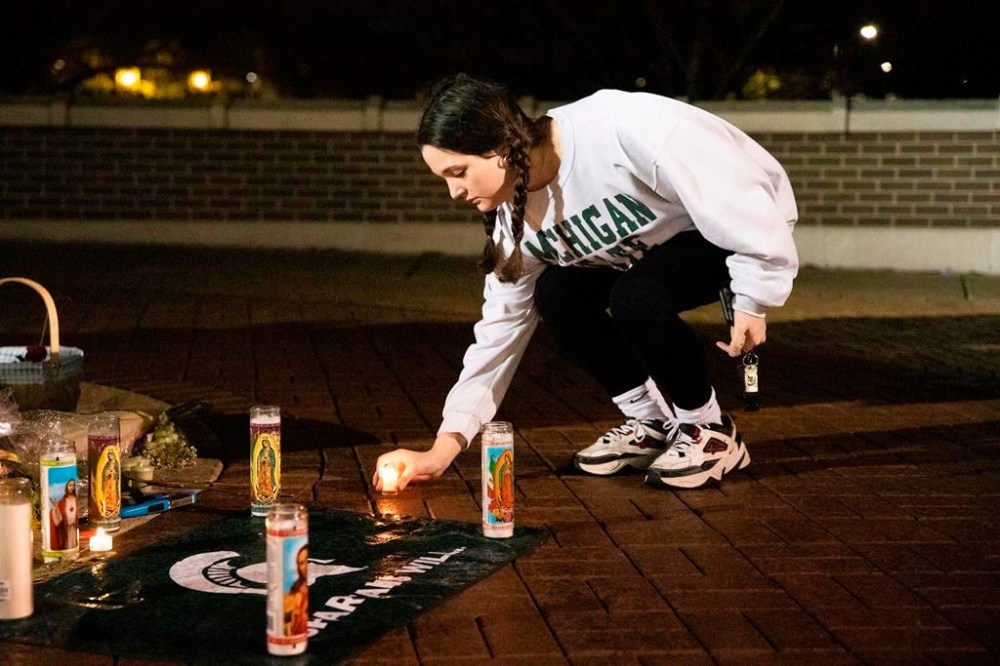 Maddie Kimball, a junior at Michigan State University from Spring Lake, Mich., lights a vigil candle at the Spartan Statue the night after a mass shooting on campus, in East Lansing, Tuesday, Feb. 14, 2023. (Brice Tucker/mlive.com/The Flint Journal via AP)