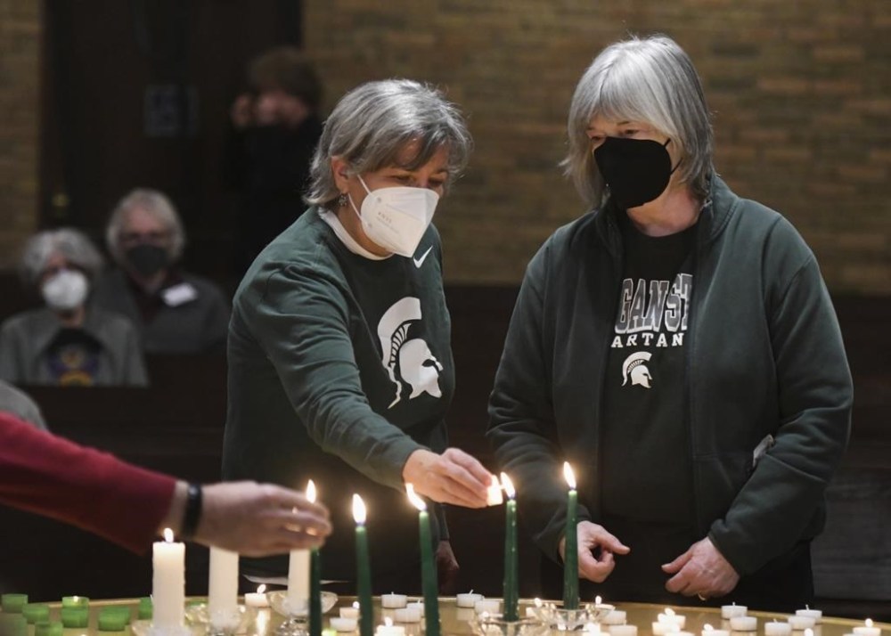 Colleen Johnson, left, and Ellen Ives light candles to honor Michigan State University students Brian Fraser, Alexandria Verner and Arielle Anderson, who died in a shooting on campus the night before, at Edgewood United Church in East Lansing, Mich., Tuesday, Feb. 14, 2023. (Matthew Dae Smith/Lansing State Journal via AP)