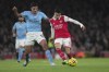 Arsenal's Gabriel Martinelli, right, kicks the ball ahead of Manchester City's Rodri during the English Premier League soccer match between Arsenal and Manchester City at the Emirates stadium in London, England, Wednesday, Feb.15, 2023. (AP Photo/Kin Cheung)