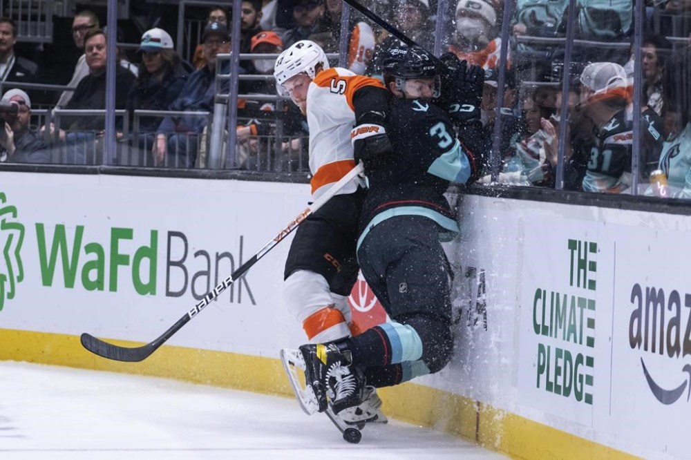 Philadelphia Flyers forward Wade Allison, left, checks Seattle Kraken defenseman Will Borgen into the boards during the third period of an NHL hockey game Thursday, Feb. 16, 2023, in Seattle. The Kraken won 6-2. (AP Photo/Stephen Brashear)