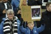 A Newcastle United fan holds up a sign in memory of Christian Atsu who has died following the devastating earthquake that hit Turkey, before the English Premier League soccer match between Newcastle United and Liverpool at St. James' Park, Newcastle upon Tyne, England, Saturday, Feb. 18, 2023. (Owen Humphreys/PA via AP)