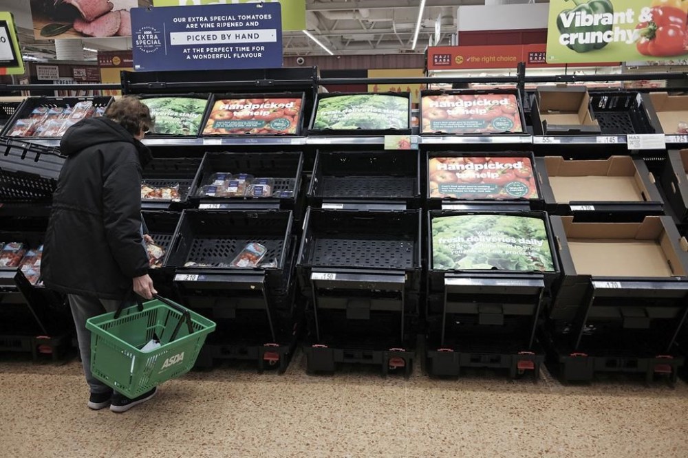 A customer checks almost empty fruit and vegetable shelves at an Asda in east London, Tuesday, Feb. 21, 2023. Several British supermarket chains have limited the amount of some fresh produce customers can buy amid shortages blamed on bad weather in Spain and Morocco. (Yui Mok/PA via AP)