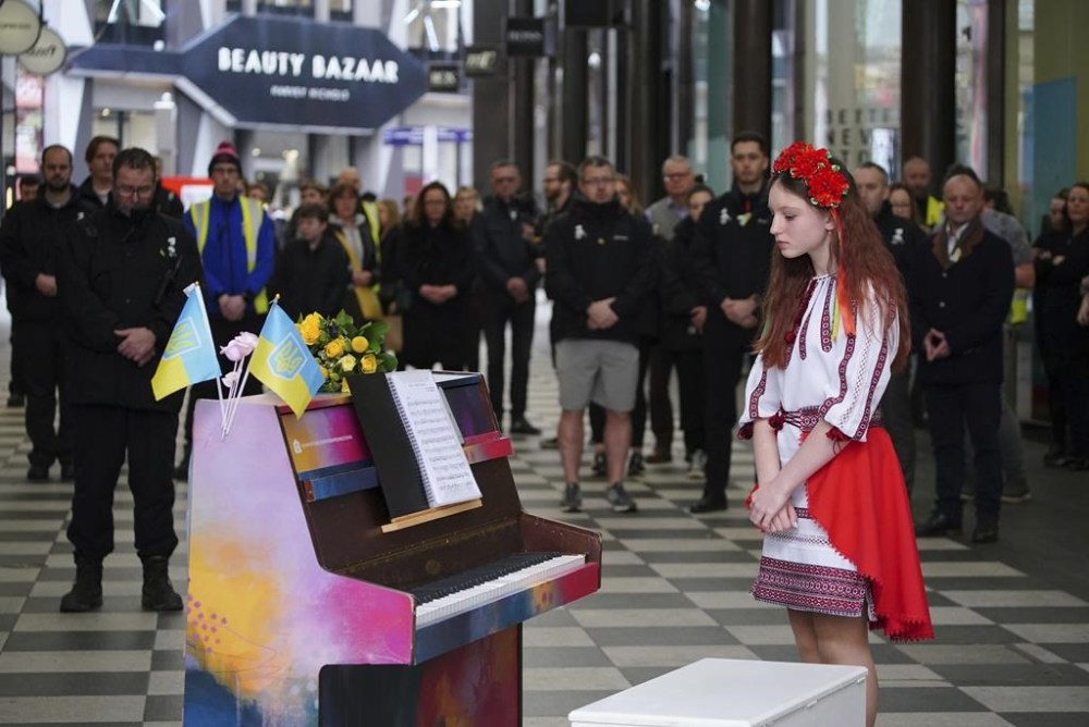 Ukrainian teenager, Alisa Bushuieva, who was forced to flee her country with her mother, Svitlana, in February last year, joins members of the public to observe a minute's silence at Peter's Lane in Liverpool, Britain, to mark the one-year anniversary of the Russian invasion of Ukraine, Friday Feb. 24, 2023. (Peter Byrne/PA via AP)