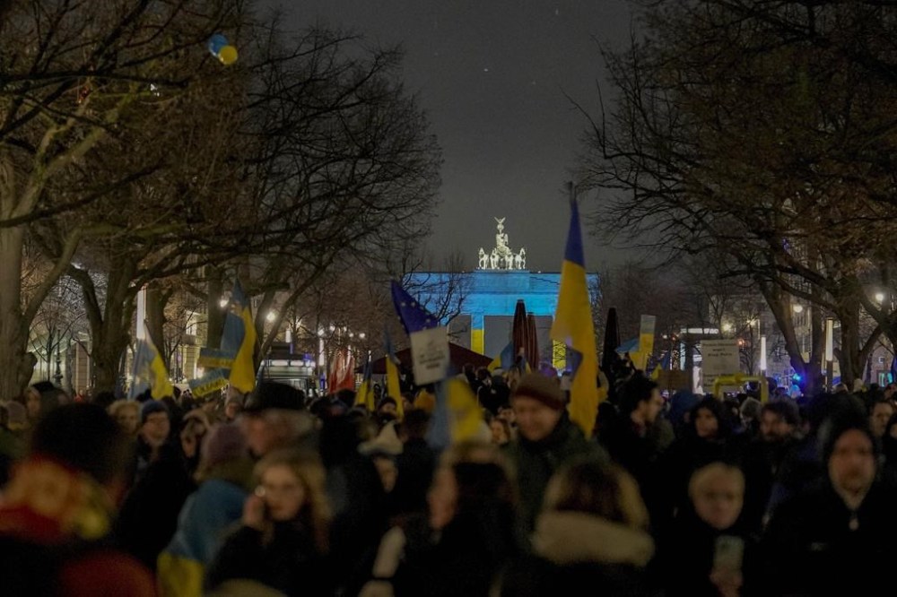 Protestors arrive at the Brandenburg Gate, illuminated in Ukrainian colors, during a demonstration to mark the first anniversary of Russia's full-scale invasion of Ukraine, in Berlin, Germany, Friday, Feb. 24, 2023. (AP Photo/Markus Schreiber)