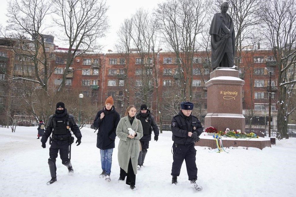 Policemen detain a young people who has laid flowers to the monument of Ukrainian author Taras Shevchenko to mark one year since the start of the Russian campaign in Ukraine in St. Petersburg, Russia, Friday, Feb. 24, 2023. OVD-Info, a group that tracks political arrests, said that several people were detained in St. Petersburg after bringing flowers to the Shevchenko monument. (AP Photo/Dmitri Lovetsky)
