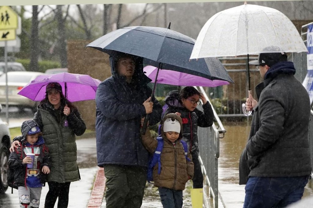 Children are dropped off at school outside Old Orchard School Friday, Feb. 24, 2023, in Newhall, Calif. California and other parts of the West faced heavy snow and rain Friday from the latest winter storm to pound the U.S.(AP Photo/Marcio Jose Sanchez)