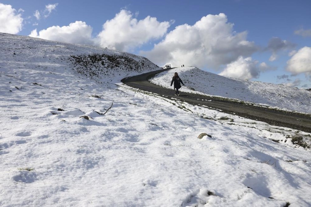 Kimberly Pong enjoys the weather as snow covers the top elevation of Las Trampas Regional Wilderness Park in San Ramon, Calif., on Friday, Feb. 24, 2023. (Ray Chavez /Bay Area News Group via AP)