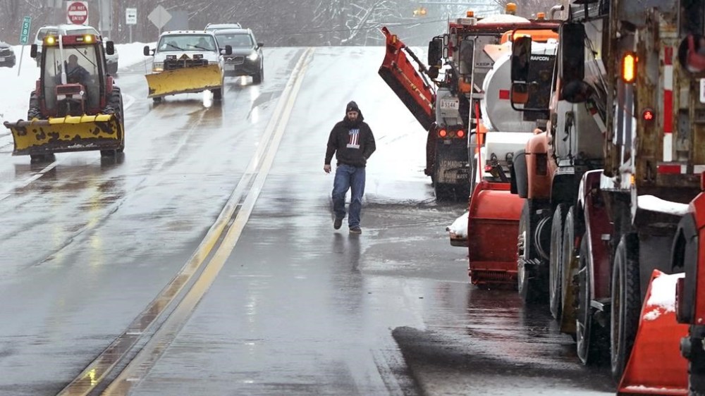 A driver walks back to his truck after a plowing convoy parked on a snow-free road near an off-ramp to Route 495, Tuesday, Feb. 28, 2023, in Haverhill, Mass. Much of the area north of Boston received about two inches of snow before turning to rain during a winter storm. (AP Photo/Charles Krupa)