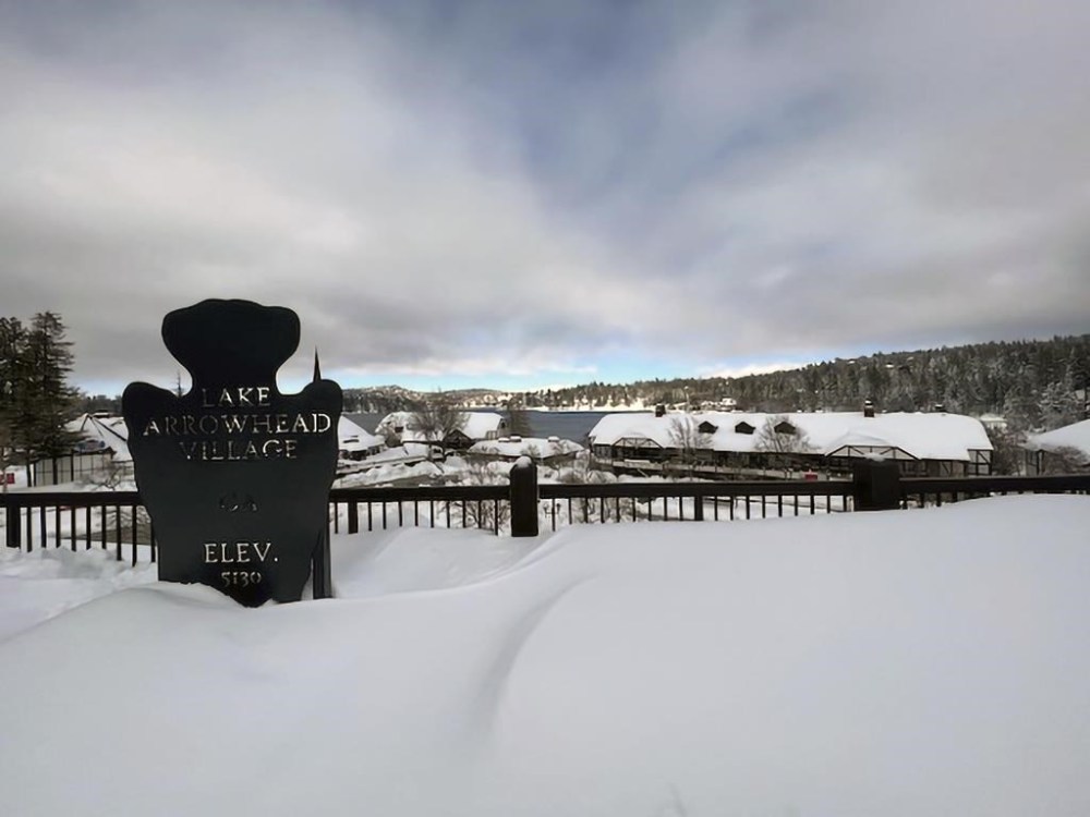 A sign for Lake Arrowhead Village is seen covered in snow on Sunday, Feb. 26, 2023 in the San Bernardino Mountains of San Bernardino County, Calif. Beleaguered Californians got hit again Tuesday as a new winter storm moved into the already drenched and snow-plastered state, with blizzard warnings blanketing the Sierra Nevada and forecasters warning residents that any travel was dangerous. (Matthew Cobb via AP)
