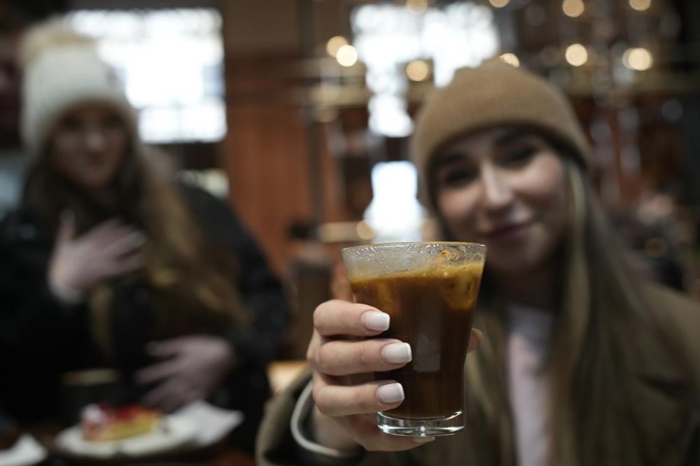 Kaya Cupial, right, shows her Oleato Iced Cortado coffee at the Starbucks coffee shop in Milan, Italy, Monday, Feb. 27, 2023. Putting olive oil in coffee is hardly a tradition in Italy, but that didn't stop Starbucks founder and CEO Howard Schultz from launching a series of beverages doing just that in Milan, the city that inspired his coffee house empire. (AP Photo/Antonio Calanni)